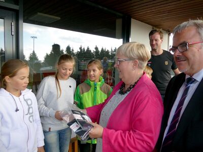 Heike Smolinski, Vorstandsmitglied der Erzgebirgssparkasse, Landrat Frank Vogel und Vize-Weltmeister Ralf Palik übergeben den neuen Schülern der Eliteschule des Wintersports in Oberwiesenthal sportliche Stirnbänder.